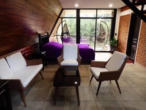 a room with white chairs and a purple bed at Cabañas El Rincón de Pancho in Altotonga