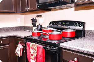 a kitchen stove with four pots and pans on it at The Monthly stay Apartment for 8, pool and grill in Greensboro