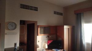 a room with a clock on the wall and a desk at EL Salam in Hotel Apartment 6 in Sharjah