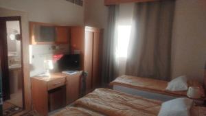 a room with two beds and a desk and a television at EL Salam in Hotel Apartment 6 in Sharjah