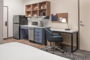 a small kitchen with a desk and a refrigerator at Candlewood Suites St. Robert by IHG in Saint Robert