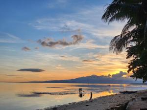 Eine Gruppe von Menschen steht bei Sonnenuntergang am Strand. in der Unterkunft Seashore Inn in Siquijor