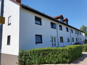 a white building with black windows and a hedge at Ferienwohnung Groß-Umstadt in Groß-Umstadt