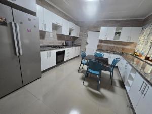 a kitchen with white cabinets and a table and chairs at Zachi Eland Apartment in Kitwe +16 photos