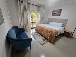 a bedroom with a bed and a blue chair at Zachi Eland Apartment in Kitwe