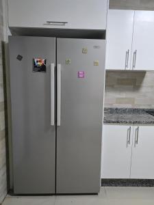 a stainless steel refrigerator in a kitchen with white cabinets at Zachi Eland Apartment in Kitwe