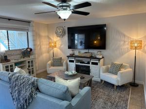 a living room with a blue couch and chairs and a tv at Harrison Lakeside Retreat in Harrison Hot Springs