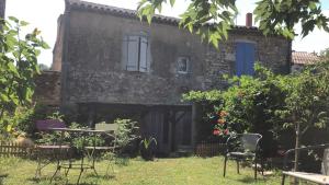 an old stone house with chairs and a table at Chambre dans Maison de campagne in Barbaste