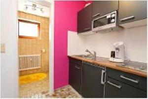 a kitchen with a pink wall and a sink at wohnung-nr-2 in Kirchzarten