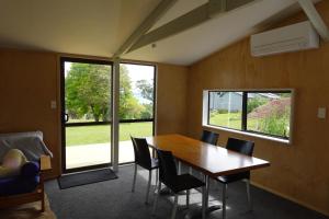 a dining room with a table and chairs and a window at One Pigeon Takatu in Tawharanui +10 photos