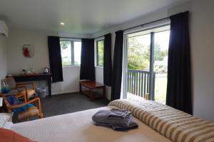 a bedroom with a bed and a desk and windows at One Pigeon Takatu in Tawharanui
