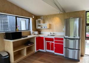 a kitchen with red cabinets and a stainless steel refrigerator at One Pigeon Takatu in Tawharanui