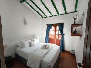 a bedroom with a large white bed with a window at Roomii Hostel in Villa de Leyva