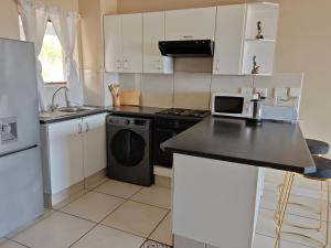 a kitchen with white cabinets and a black appliance at Vene's Place in Mossel Bay
