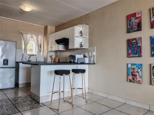 a kitchen with a counter and two bar stools at Vene's Place in Mossel Bay