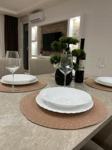 ein Tisch mit zwei weißen Tellern und Weingläsern in der Unterkunft Gold Star Apartman in Ruma
