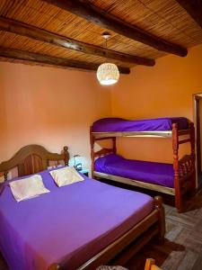 two beds in a room with purple sheets at Casa Mamani in Tilcara
