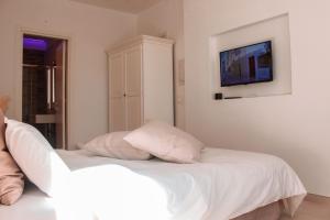 a bedroom with a white bed with a tv on the wall at Dimora Caggione in Polignano a Mare