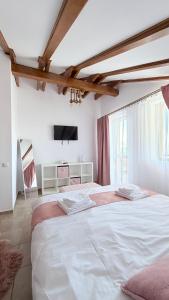 a bedroom with a large white bed and a tv at Ammon Mountain Villas in Bran