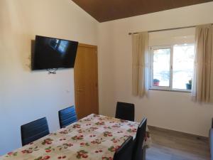 a dining room with a table and a television on the wall at MONTE DO SALTO DA RAPOSA in Figueira e Barros