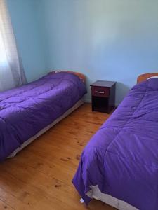 a bedroom with two beds and a table with a purple comforter at Puyehue in Mantilhue