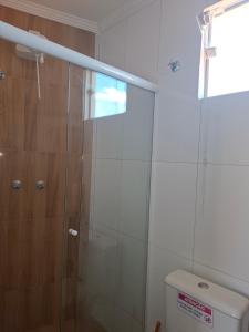 a shower with a glass door next to a toilet at Suítes da Rô - hospedaria familiar diária e temporada in Varginha