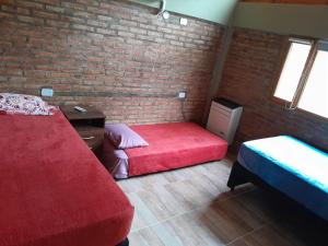 a bedroom with two beds and a brick wall at Cabaña Cholito in Lago Puelo