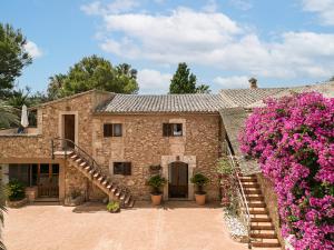a stone house with a staircase and pink flowers at Finca Es Torrent in Campos
