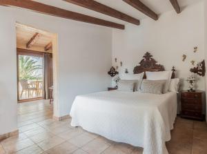 a bedroom with a white bed with a wooden headboard at Finca Es Torrent in Campos