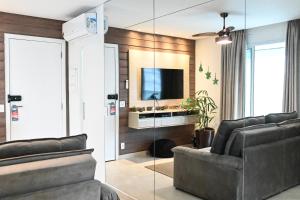 a living room with a couch and a television at Flat Alto Padrão Quadra da Praia in Santos