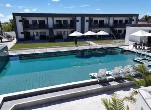 a large swimming pool with chairs and umbrellas at Brisa Mar Prime in Porto Seguro