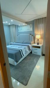 a bedroom with a large bed and a table with a lamp at Dgomez House in Santiago de los Caballeros