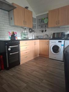 eine Küche mit Holzschränken und einer Waschmaschine und einem Trockner in der Unterkunft An Crann Glas in Galway