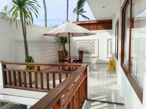 a balcony with a table and an umbrella at Artha Sadia Villa 2 Seseh Beach in Cemagi