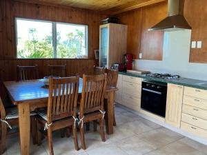 a kitchen with a wooden table with chairs and a stove at Blue Horizon Hideaway in Matapouri