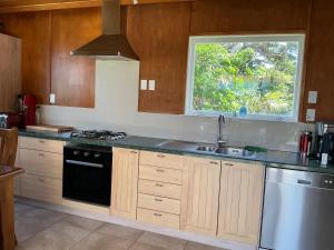 a kitchen with wooden cabinets and a sink and a window at Blue Horizon Hideaway in Matapouri +27 photos
