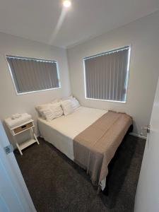 a small bedroom with a bed and two windows at Unique homestay in Auckland