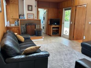 a living room with a leather couch and a television at Blue Horizon Hideaway in Matapouri