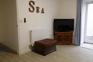 a living room with a chair and a television at Converted Coastal Coach House in Weston-super-Mare