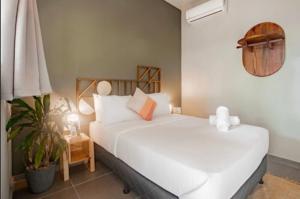 a bedroom with two white beds and a plant at Selina Venao Beach West in Playa Venao