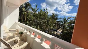 a balcony with white chairs and palm trees at Hotel Juan Dolio in Juan Dolio