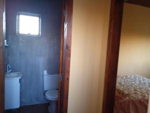 a small bathroom with a toilet and a window at Casa sobrado in Alegrete +3 photos