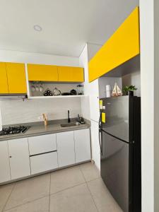a kitchen with yellow and white cabinets and a refrigerator at GabyMar salinas del mar Santamarta in Santa Marta