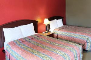 two beds in a hotel room with red walls at Express Inn Thomson in Thomson