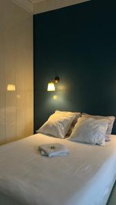 a large bed with white pillows and a green wall at Hotel - Bar - LES PASSIONS in Buis-les-Baronnies
