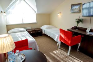a hotel room with two beds and a desk and two chairs at Hotel Alexandra in Pobiedziska