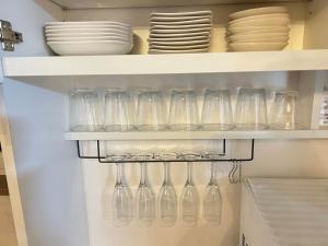 a cupboard with glasses and plates on a shelf at garden villa 月灯tsukibi in Shiraoi