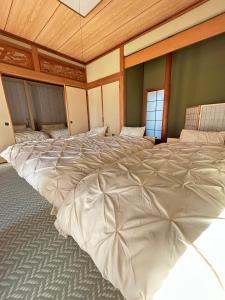 a large white bed in a room with windows at garden villa 月灯tsukibi in Shiraoi