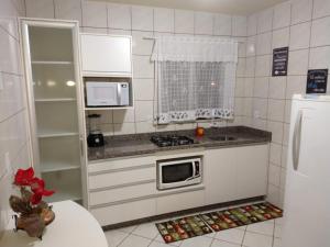 a small kitchen with a stove and a refrigerator at Murilo House - Apart-hotel completo e privativo in São José