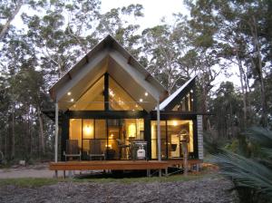 a tiny house in the woods with a large glass facade at The Bower At Broulee in Broulee